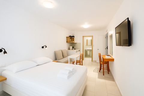 Bright studio with double bed, sofa, kitchenette, desk and wall-mounted TV