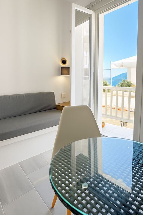Glass table and sofa by open doors to a balcony with sea view