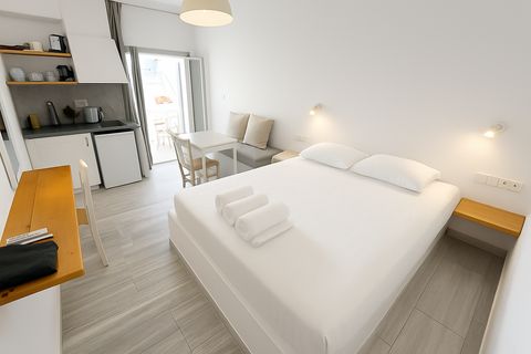 Double bed, kitchenette and dining table near doors opening onto a balcony