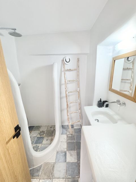 Bathroom with curved walk-in shower, patterned tiles, decorative ladder and gilt-framed mirror